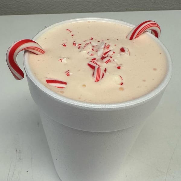 A Nubbin's Drive-In peppermint milkshake in a white styrofoam cup, garnished with candy canes.